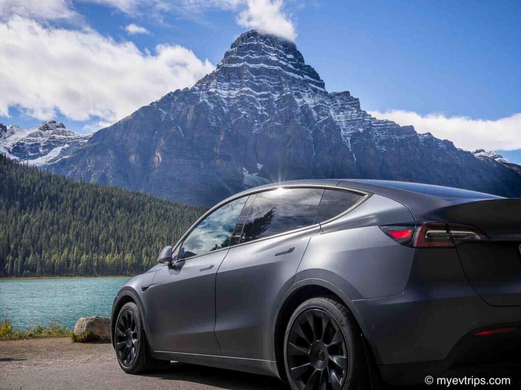 Tesla Model Y parked next to lake with mountains in background an Ice Field parkway in Alberta