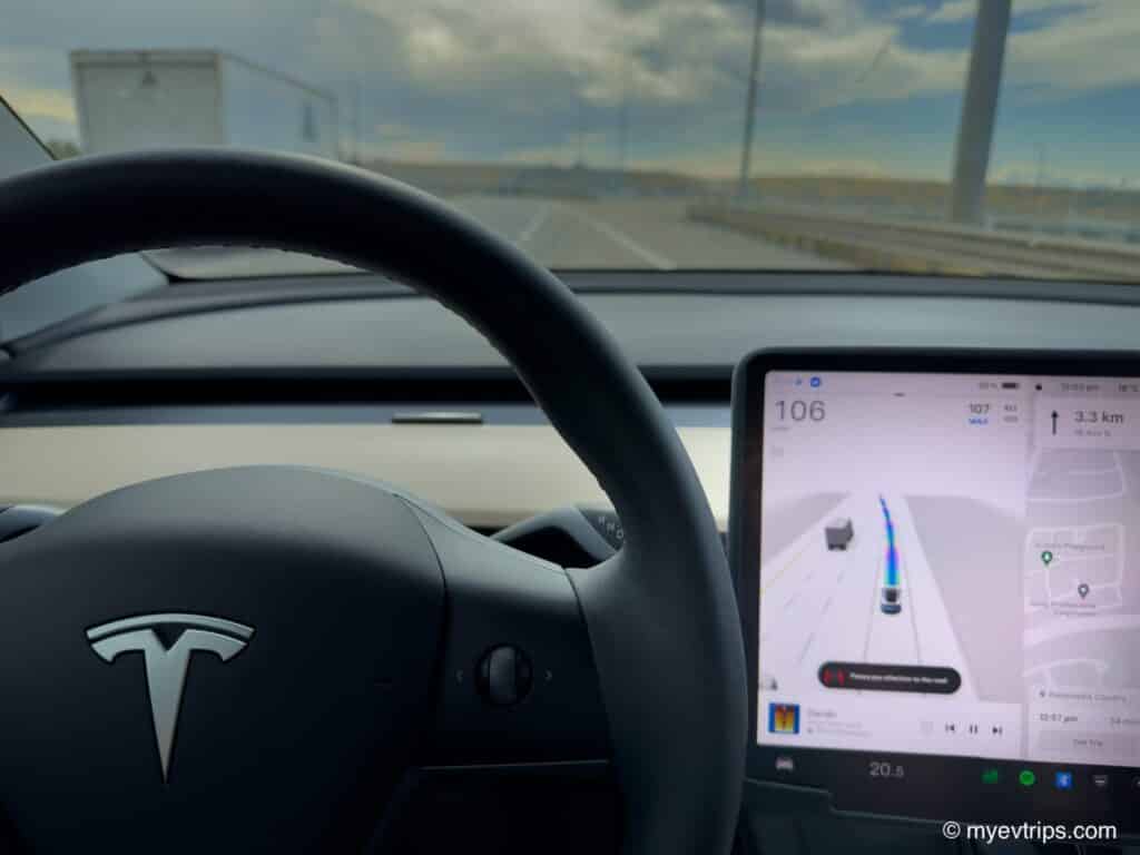 Tesla Model Y dashboard with Tesla FSD V12 engaged on highway, overtaking large truck