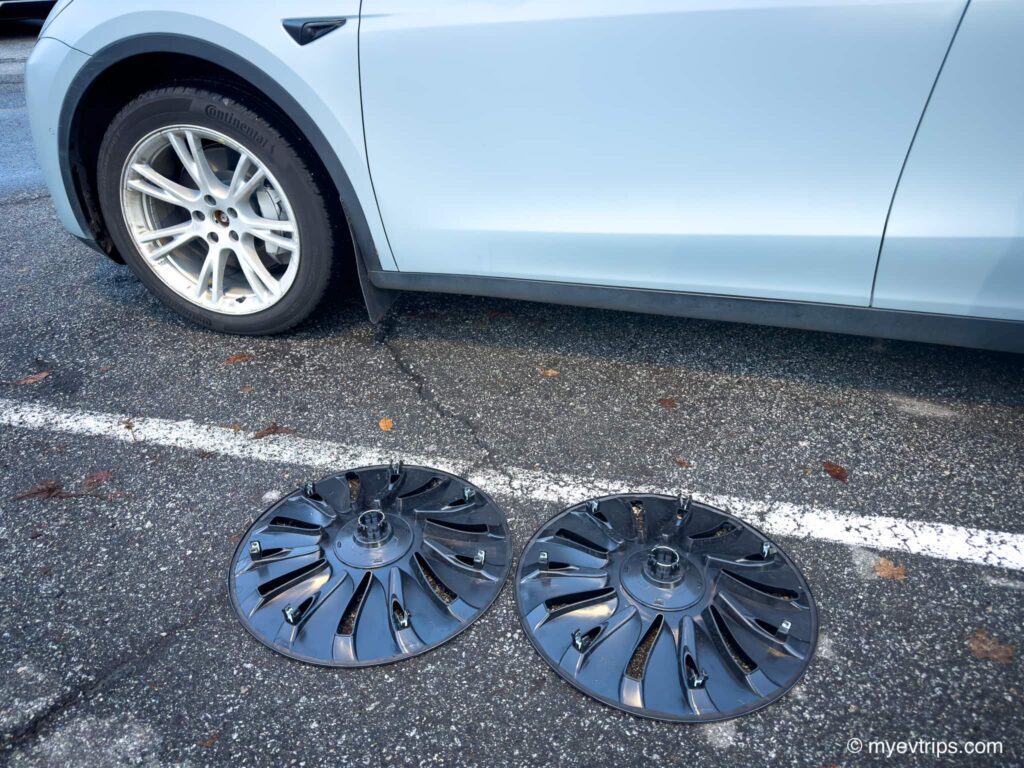 Model y without wheel covers with two Uberturbine covers on the gorund in front of it