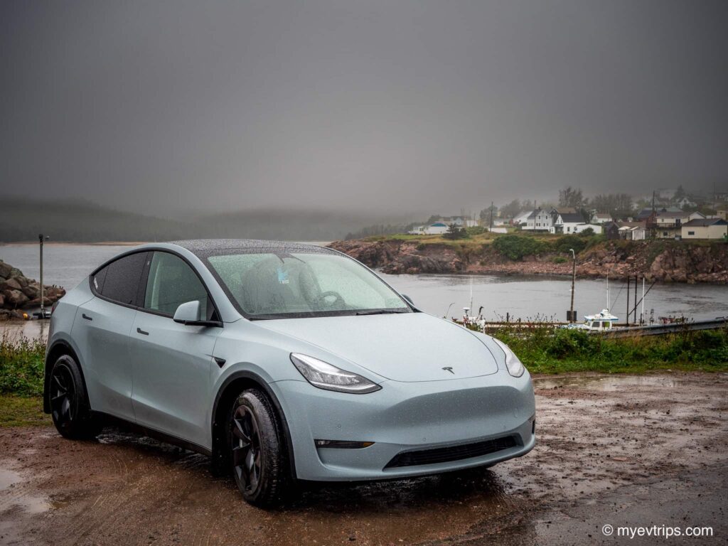 Tesla Model Y in grey rain next to harbour in Nova Scotia