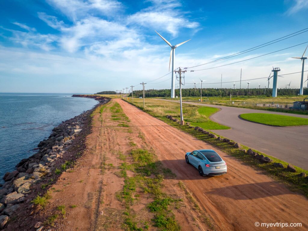 Tesla Model Y driving next to wind turbines at North Cape, PEI