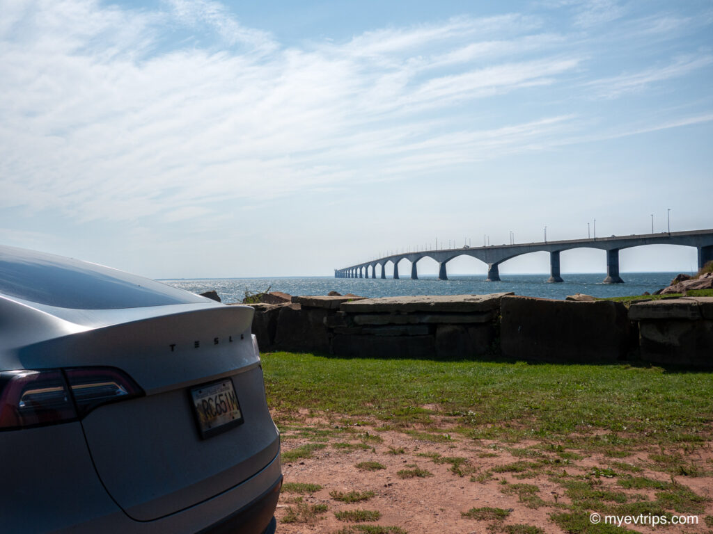 Backend of a Tesla Model Y with the Confederation Bridge in the background 