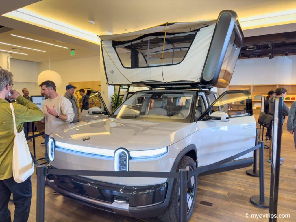 Rivian R2 on display with trunk open and tent on top