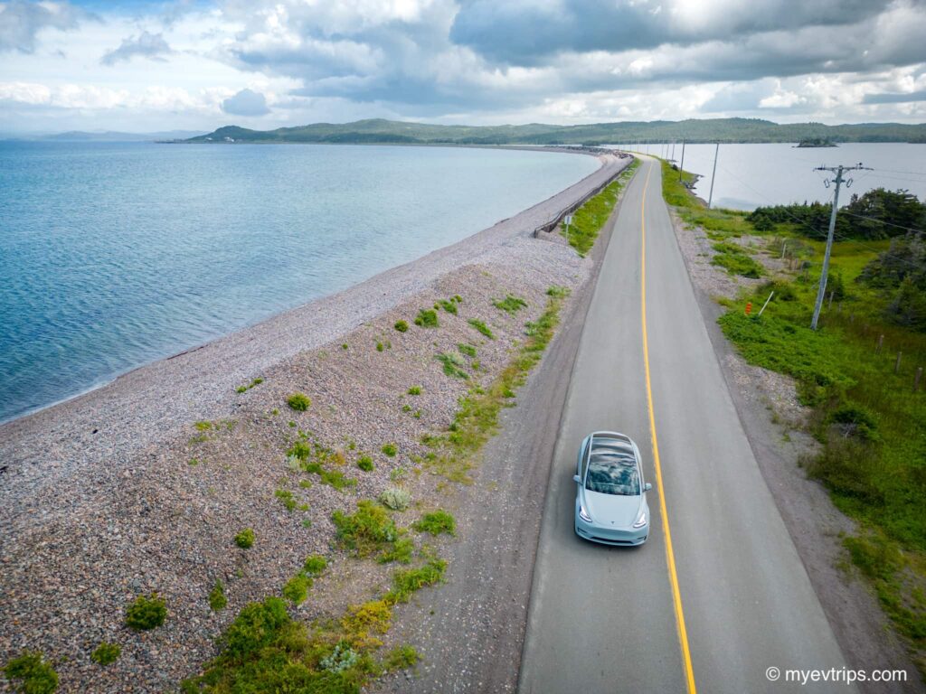 Tesla Model Y driving on a beachside road on way to Fortune Newfoundland as part of a Saint Pierre et Miquelon EV road trip