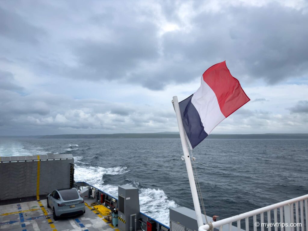 Tesla Model Y on SPM ferry to Fortune Newfoundland with France flag in foreground 