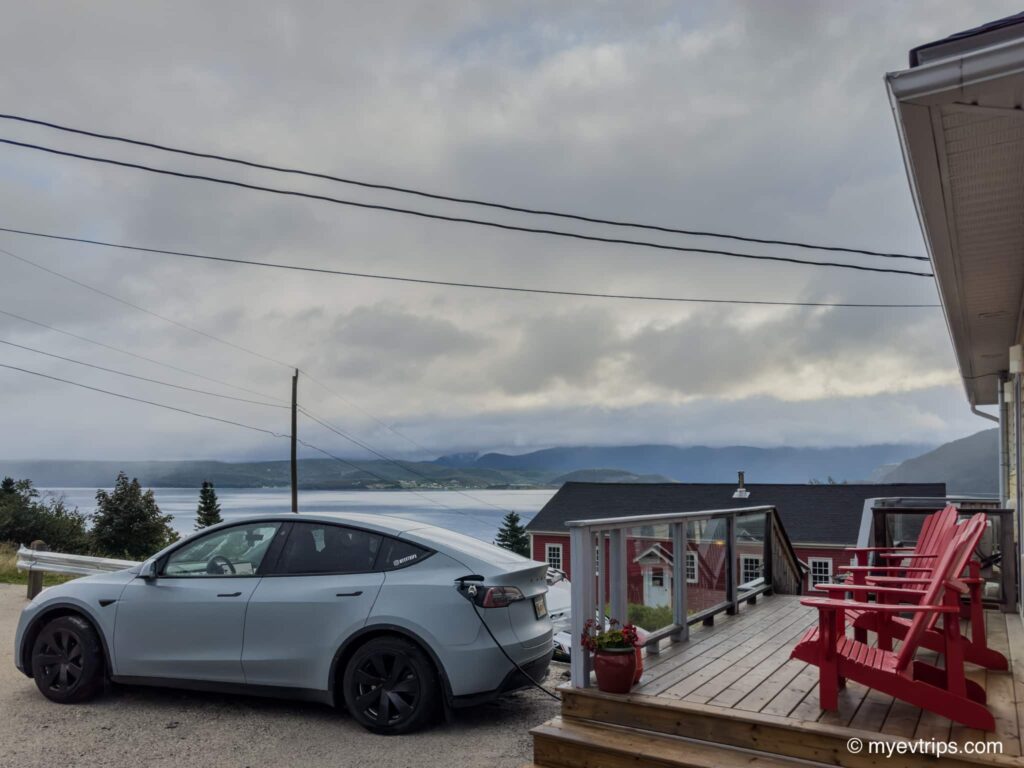 Tesla Model Y charging next to patio with red chairs on it