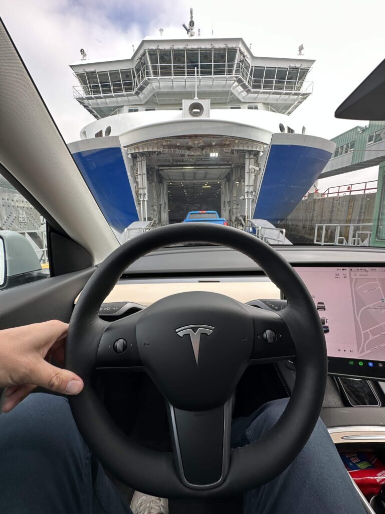 Tesla Model Y steering wheel driving onto a ferry on a Cote Nord road trip