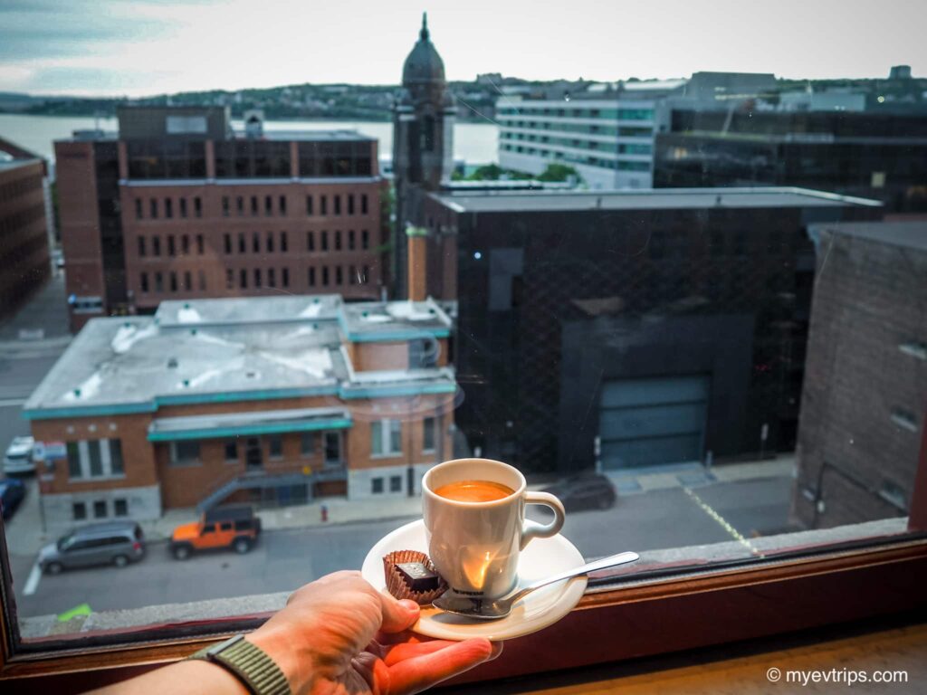 hand holding cup of coffee in front of window at Le Germain hotel in Quebec City