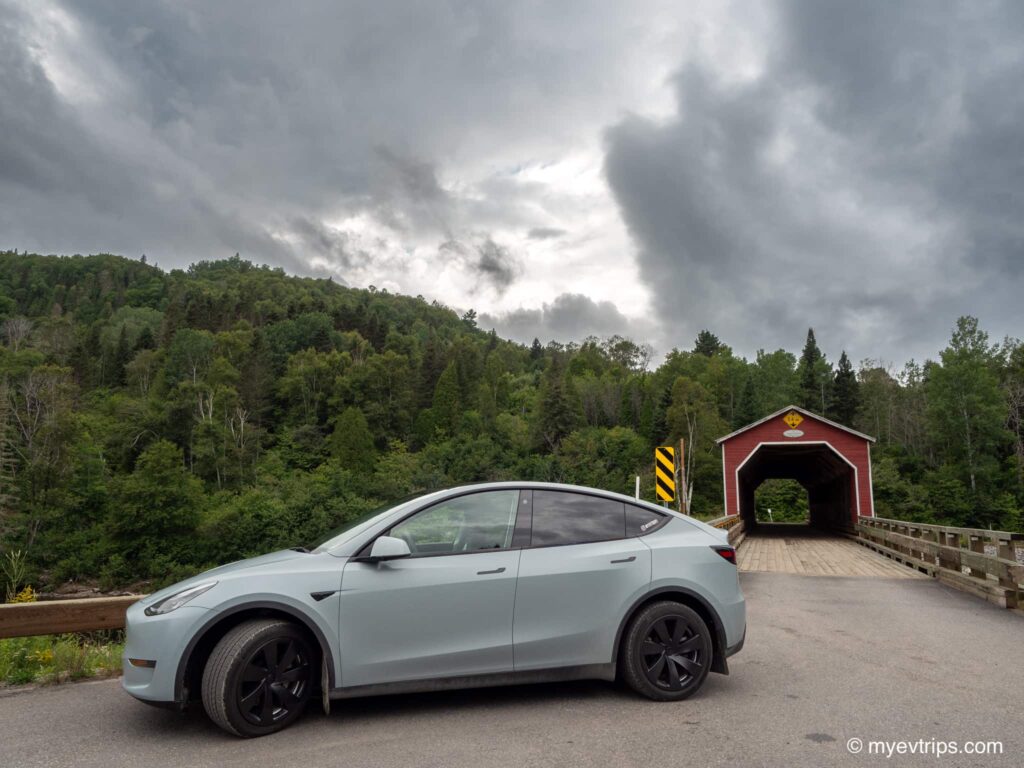 Tesla Model Y in front of Covered bridge on drive from Saguenay to Tadoussac
