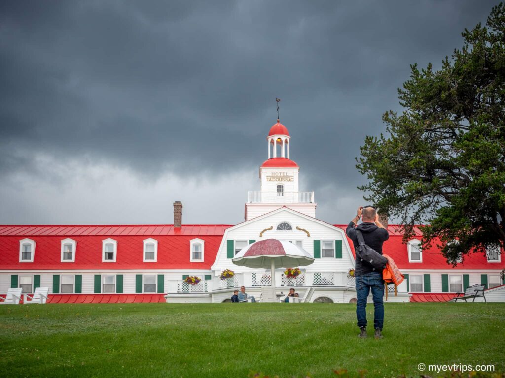 Man taking a photo in front of the Hotel Tadoussac