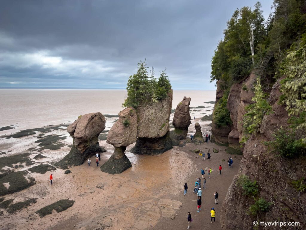 People standing next to Hopewell Rocks at low tide in New Brunswick