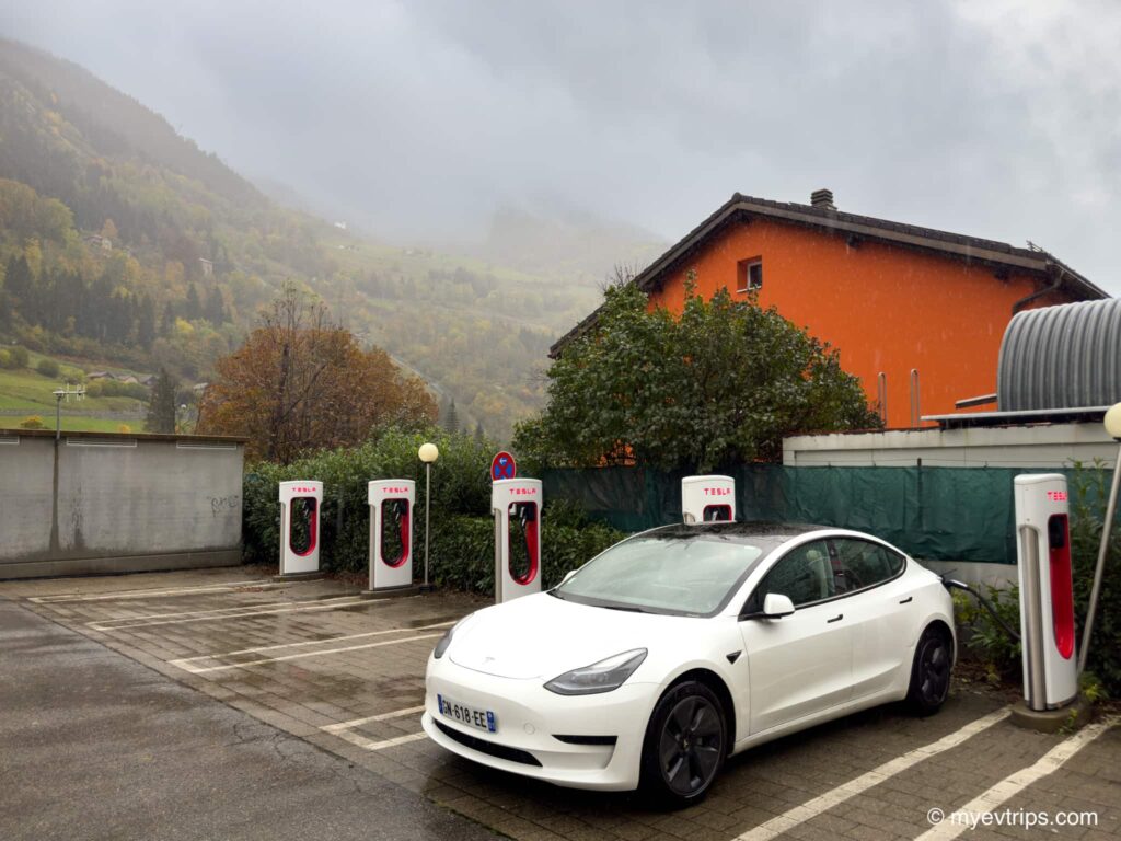 Tesla Model 3 on a Swiss alps road trip charging at a Supercharger