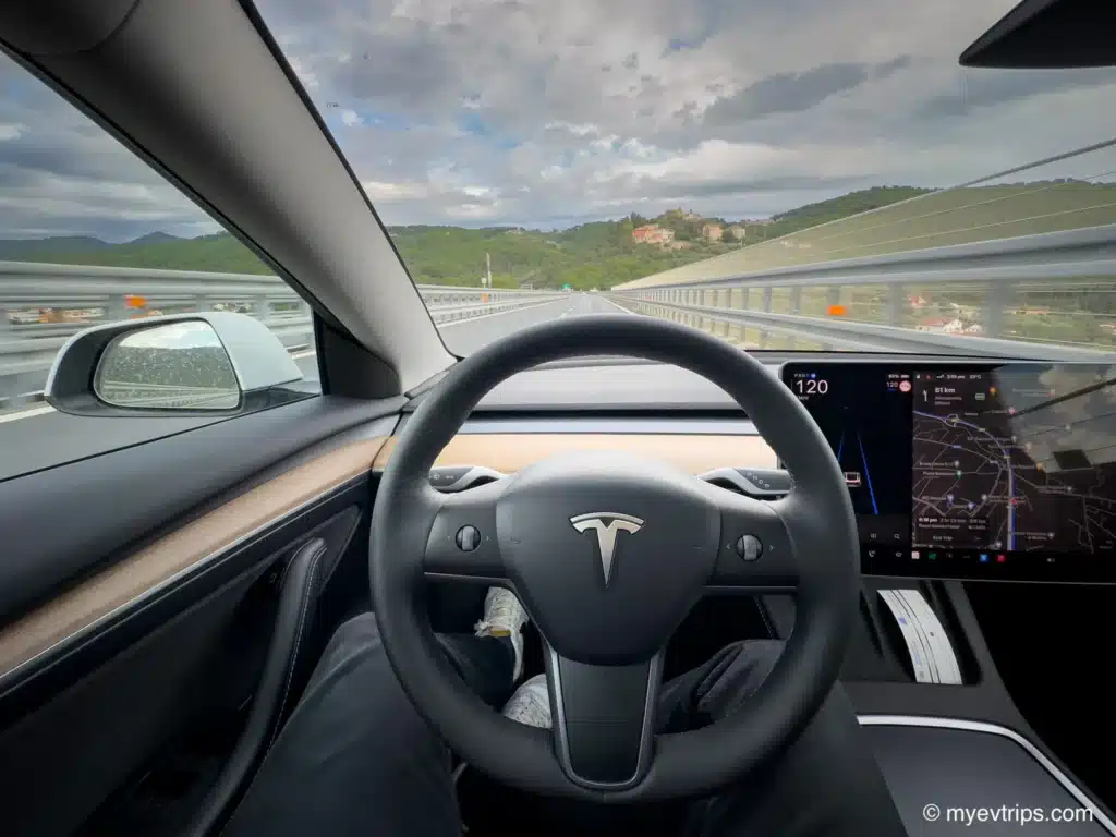 Tesla Model 3 steering wheel while driving on an Italian road trip